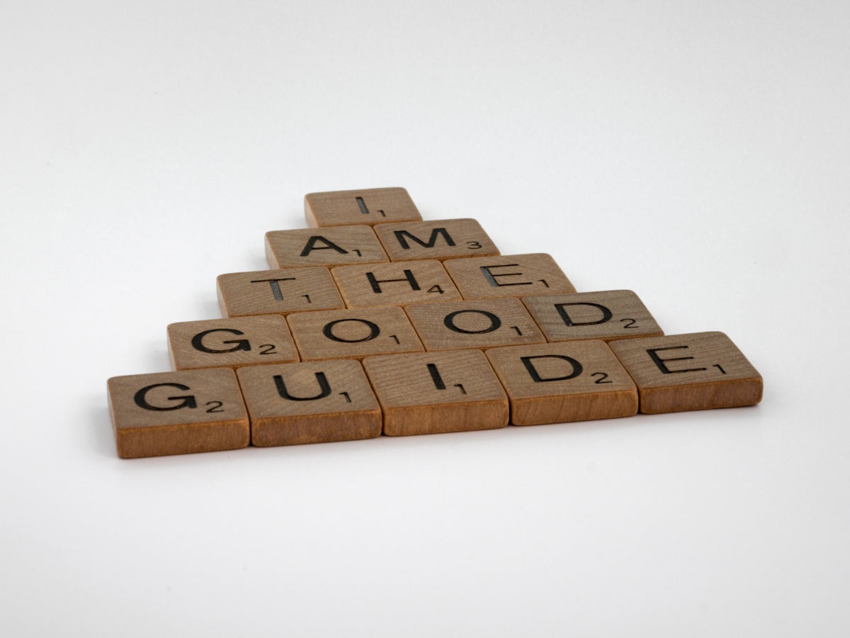 a wooden scrabble with words that read i am the good guide